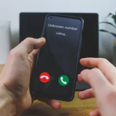 Dłoń trzyma telefon, na ekranie którego wyświetla się "Unknown number calling...". Czy to ważny numer prywatny?