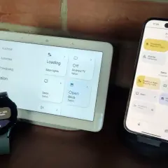 Zegarek z Wear OS i smartfon sterują inteligentnym domem. Na ekranach widać sterowanie oświetleniem i roletami w salonie.