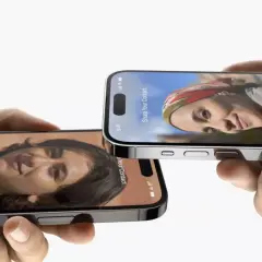 Dwie dłonie trzymają iPhone'y z funkcją udostępniania kontaktów w iOS 17. Na ekranach widnieją zdjęcia i dane Sonali Sanghvi oraz Athirah Abdullah.