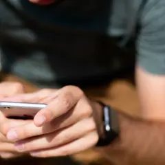 Mężczyzna z zegarkiem na ręku trzyma smartfon, przygotowując się do sparowania zegarka z telefonem.