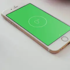 Złoty telefon z zielonym ekranem, na którym widnieje ikona poziomicy. Obok stoi niebieska szklanka.