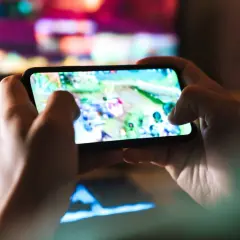 Dłonie trzymają smartfon z grą. Szybkość 5G co to? To płynna rozgrywka mobilna bez lagów, idealna do gier online.