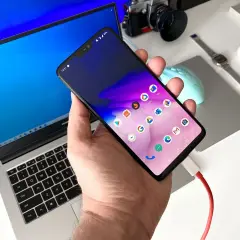 Podłączony do laptopa smartfon, gotowy do transferu danych. Prosty sposób, jak przesłać zdjęcia z telefonu na komputer.