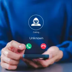 Osoba trzyma smartfon z ekranem pokazującym połączenie od nieznanego numeru. Dowiedz się, jak zablokować numer prywatny, aby uniknąć niechcianych rozmów.