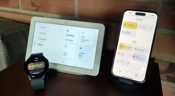 Zegarek z Wear OS i smartfon sterują inteligentnym domem. Na ekranach widać sterowanie oświetleniem i roletami w salonie.
