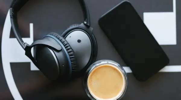 Słuchawki bezprzewodowe, smartfon i kawa – idealny zestaw do tworzenia rankingu słuchawek bezprzewodowych.