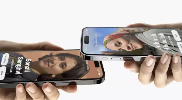Dwie dłonie trzymają iPhone'y z funkcją udostępniania kontaktów w iOS 17. Na ekranach widnieją zdjęcia i dane Sonali Sanghvi oraz Athirah Abdullah.