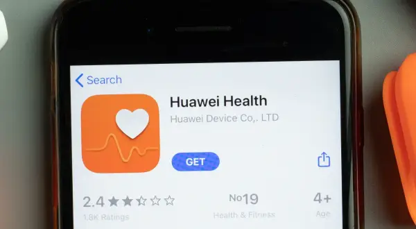 Ekran telefonu z aplikacją Huawei Health. Ikona serca z pulsem, przycisk "GET". W tle pomarańczowy przedmiot.