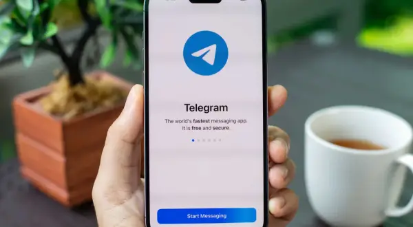 Dłoń trzyma smartfon z ekranem powitalnym aplikacji Telegram. Dowiedz się, telegram co to za szybka i bezpieczna aplikacja do komunikacji.
