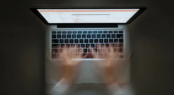 Ręce szybko piszą na klawiaturze laptopa. Widać ekran z kodem. Szybkie pisanie to jak zaznacz wszystko skrót.
