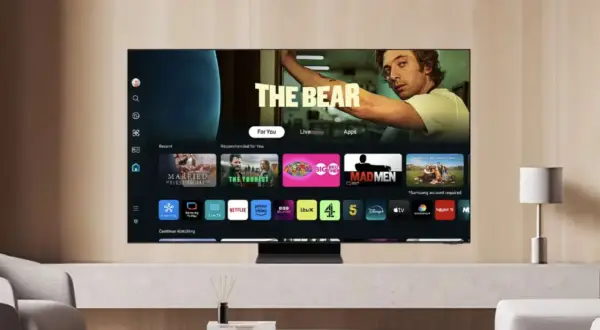 Telewizor z systemem Tizen prezentuje interfejs z filmami i serialami, w tym "The Bear". Widoczne są ikony aplikacji: Netflix, Prime Video, Disney+.