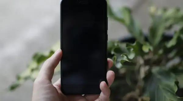 Dłoń trzyma czarny iPhone. Chcesz wiedzieć, jak wyłączyć iPhone?