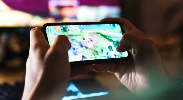 Dłonie trzymają smartfon z grą. Szybkość 5G co to? To płynna rozgrywka mobilna bez lagów, idealna do gier online.