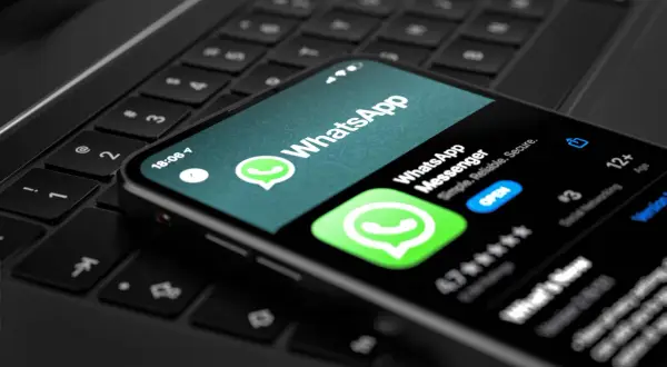 Smartfon z aplikacją WhatsApp na klawiaturze laptopa. Teraz możesz korzystać z WhatsApp na komputerze.