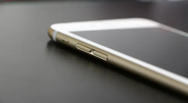 Złoty iPhone leży na ciemnym blacie. Wiesz, jak znaleźć iPhone, gdy go zgubisz?