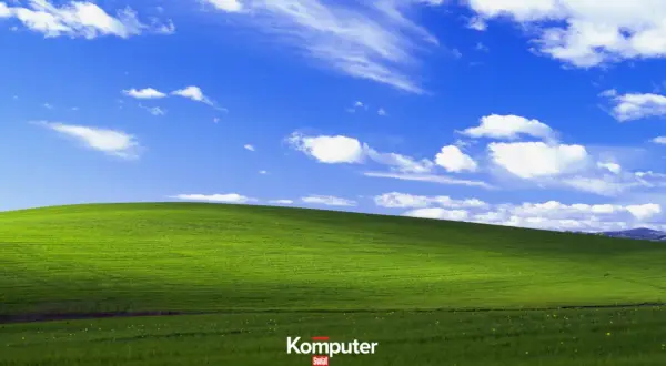 Zielone wzgórze pod błękitnym niebem z białymi chmurami, ikoniczny krajobraz z **Windows XP**.