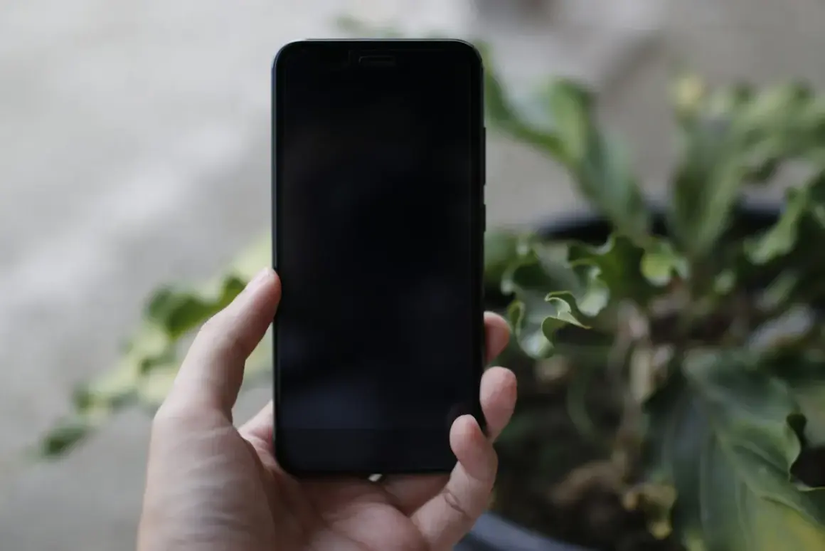 Dłoń trzyma czarny iPhone. Chcesz wiedzieć, jak wyłączyć iPhone?