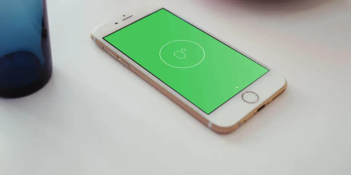 Złoty telefon z zielonym ekranem, na którym widnieje ikona poziomicy. Obok stoi niebieska szklanka.