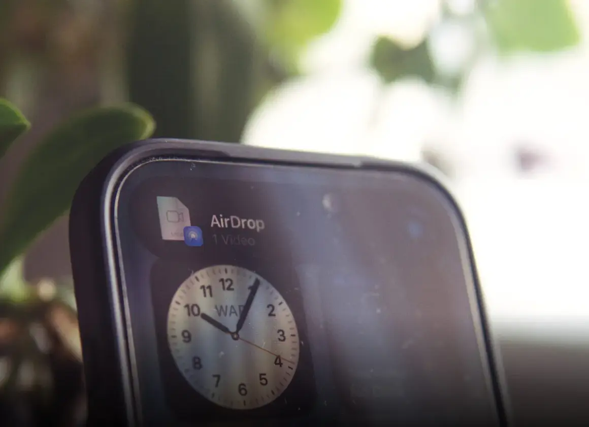 Szybki udostępnianie wideo przez AirDrop. Na ekranie telefonu widoczny jest zegar.