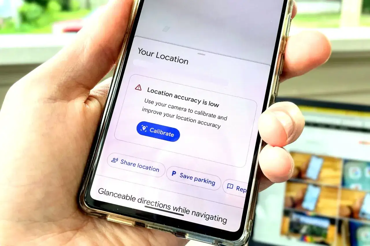 Dłoń trzyma telefon z komunikatem o niskiej dokładności lokalizacji. Widać przycisk 