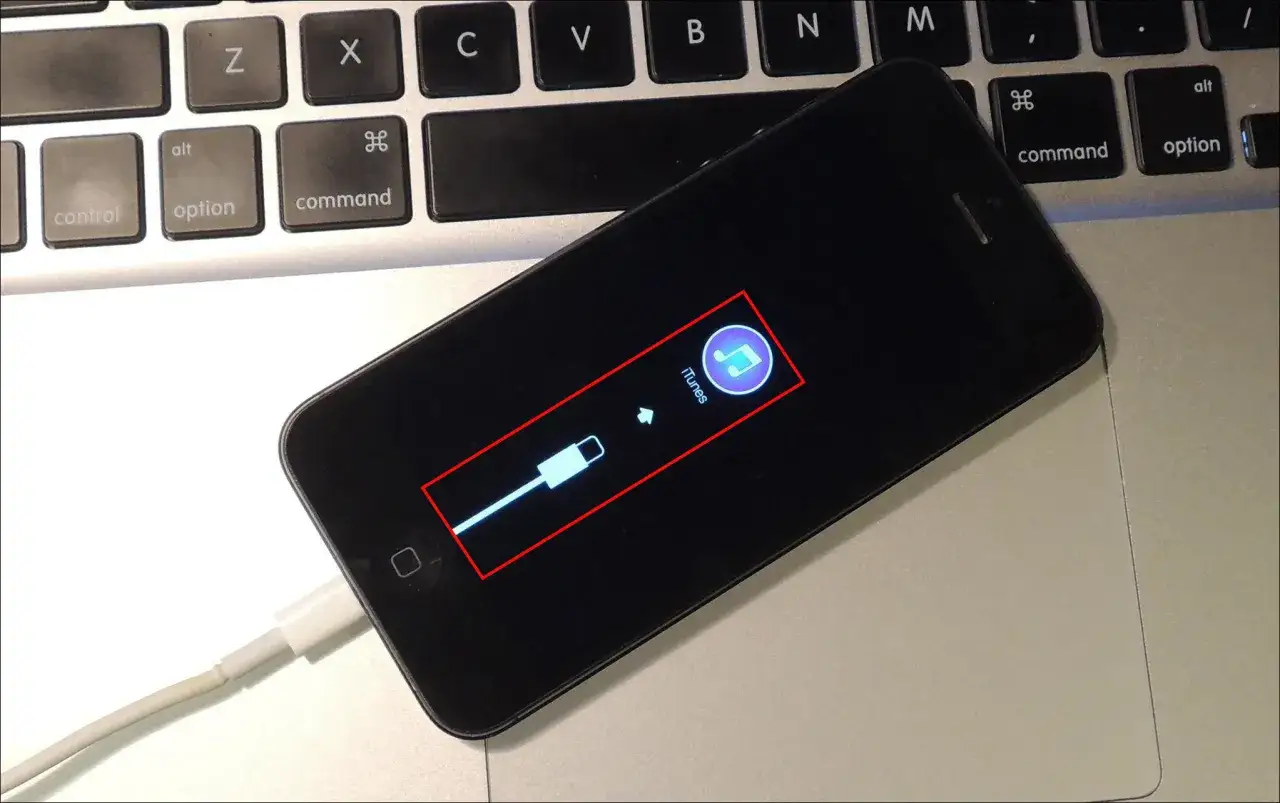 iPhone podłączony do komputera, ekran pokazuje ikonę iTunes i kabel. Tak wygląda ekran, gdy chcesz odblokować iPhone.