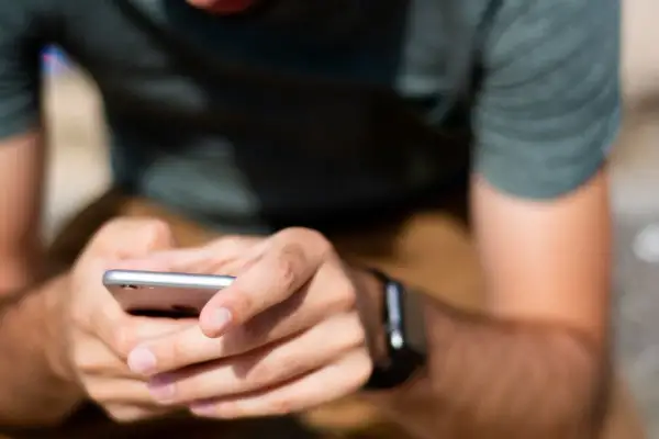 Mężczyzna z zegarkiem na ręku trzyma smartfon, przygotowując się do sparowania zegarka z telefonem.