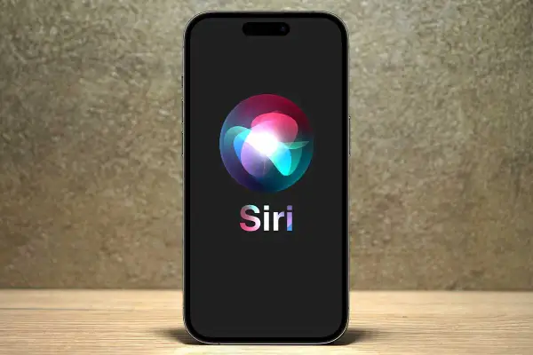 Na ekranie telefonu widnieje logo Siri, które wygląda jak kolorowa, świetlista kula.