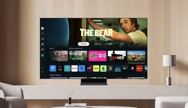 Telewizor z systemem Tizen prezentuje interfejs z filmami i serialami, w tym "The Bear". Widoczne są ikony aplikacji: Netflix, Prime Video, Disney+.