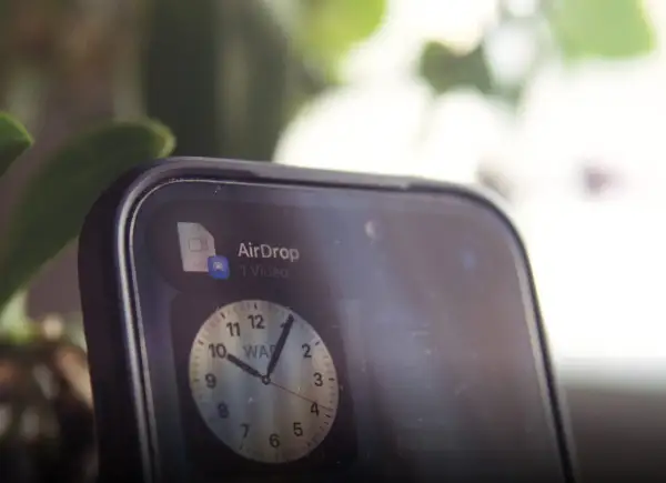 Szybki udostępnianie wideo przez AirDrop. Na ekranie telefonu widoczny jest zegar.