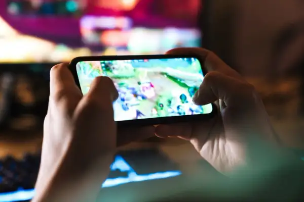 Dłonie trzymają smartfon z grą. Szybkość 5G co to? To płynna rozgrywka mobilna bez lagów, idealna do gier online.